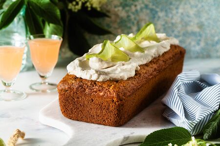 summer sweet loaf cake on a table with flowers and a drink in glasses. with coconut cream and lime. dessert for brunch or morning breakfastの写真素材