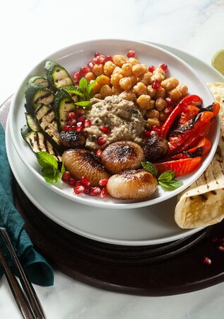 Italian Mediterranean Buddha bowl with Baba ghanoush caramelized onions, spicy chickpeas and grilled vegetables. healthy vegan food and pita breadの写真素材