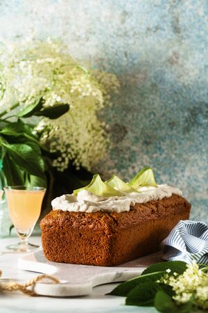 summer sweet loaf cake on a table with flowers and a drink in glasses. with coconut cream and lime. dessert for brunch or morning breakfastの写真素材