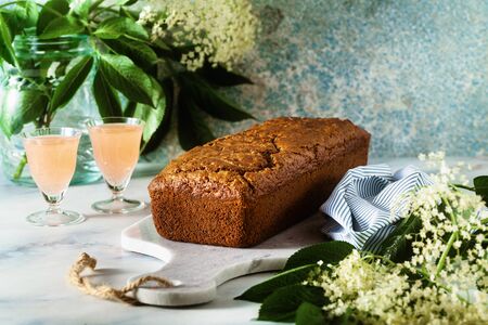 summer sweet loaf cake on a table with flowers and a drink in glasses. dessert for brunch or morning breakfastの写真素材