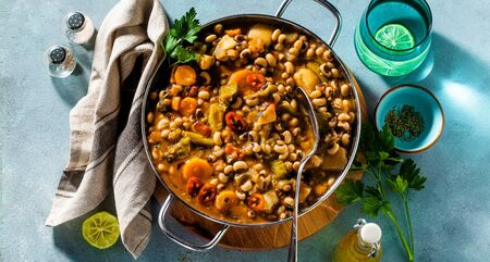 banner of Black-eyed Pea Vegan Chili in a metal pan on a wooden stand on a blue backgroundの写真素材