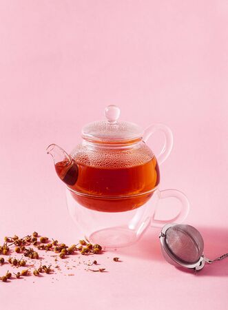 tea in a glass teapot on a pink background and a metal Infuser Filterの写真素材