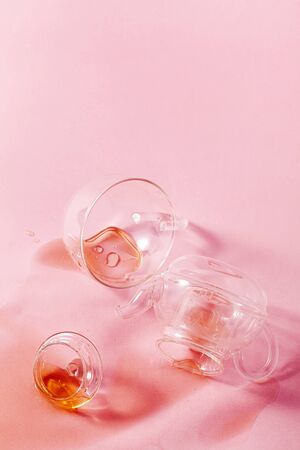thrown glass teapot and spilled tea on a pink background. abstractの写真素材