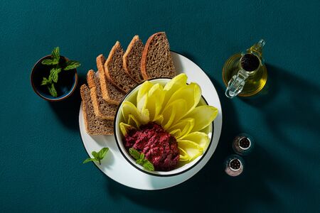 vegan snack of spread of roasted beets and pistachios and leaves of Belgian Endive with whole grain bread on the tableの写真素材