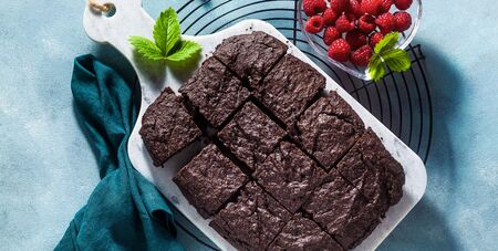 banner of chocolate vegan brownie pie with tahini and fresh raspberries on a blue backgroundの写真素材