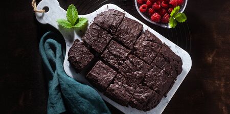 banner of chocolate vegan brownie pie with tahini and fresh raspberries on a dark backgroundの写真素材