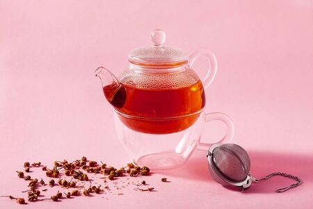 tea in a glass teapot on a pink background and a metal Infuser Filterの写真素材