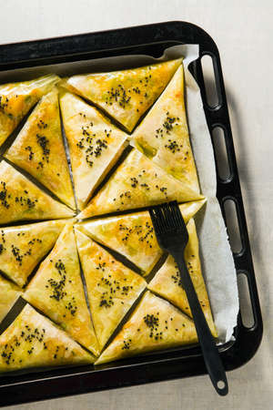 indian samosa made with phyllo with spicy potatoes and vegetables on a baking sheet, ready to be baked in the oven with black sesame seedsの写真素材