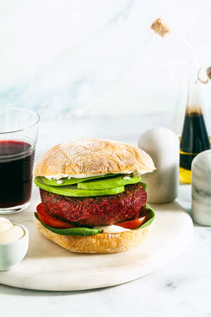 vegan burger without meat with avocado, tomatoes and spinach on the table and red wine in a glassの写真素材
