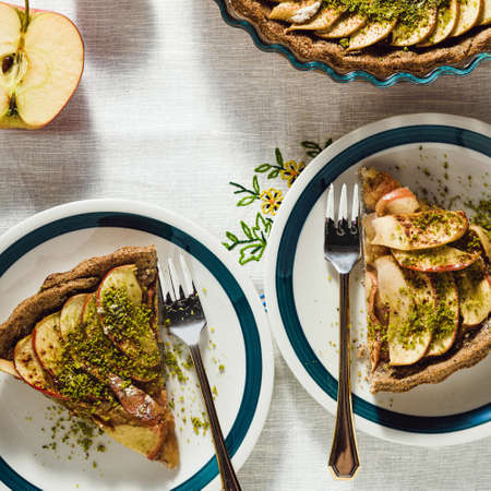 italian apple pie crostata with pistachio crumbs on the table with a white tableclothの写真素材