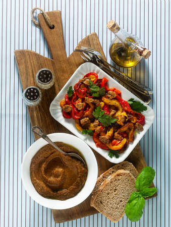 summer snacks of sweet peppers and sun-dried tomato cream with bread and spices on the tableの写真素材