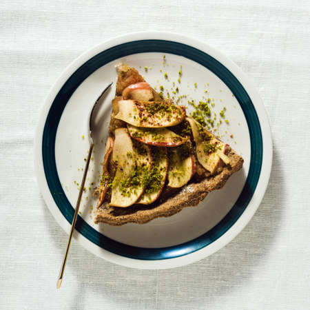 italian apple pie crostata with pistachio crumbs on the table with a white tableclothの写真素材