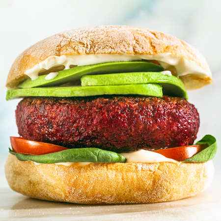 vegan burger without meat with avocado, tomatoes and spinach on the table and red wine in a glassの写真素材