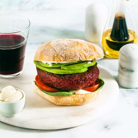vegan burger without meat with avocado, tomatoes and spinach on the table and red wine in a glassの写真素材