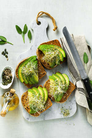 homemade tomato bread sandwiches with seeds and sun-dried tomatoes, served with avocado, sprouts and hemp seeds. a healthy morning breakfast or snackの写真素材