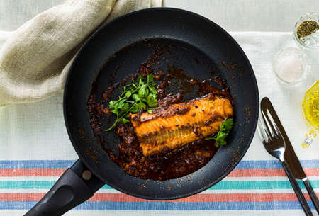 fillet of pink salmon in tomato-coconut sauce in a non-stick frying pan with parsley on a table with a linen tablecloth. healthy family foodの写真素材