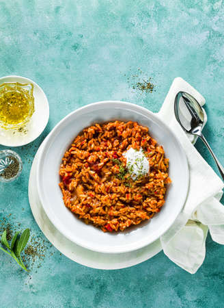 risotto with caramelized onions, tomatoes and coconut cream on a plate on the table. mix of Asian and Mediterranean cuisineの写真素材