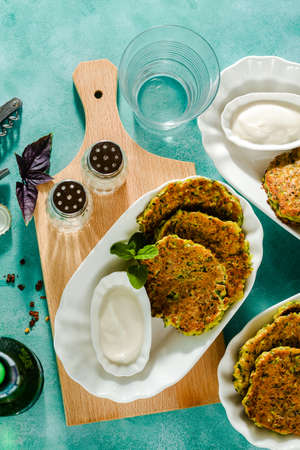 salted pancakes with zucchini and chickpea flour with spicy yoghurt sauce with beer on the table. summer vegan snack for family or lunch for friendsの写真素材