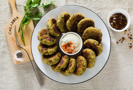 delicious vegan eggplant cutlets with yogurt and hot pepper sauce, cuisine of the Calabria region in Italy on a linen tablecloth on the tableの写真素材