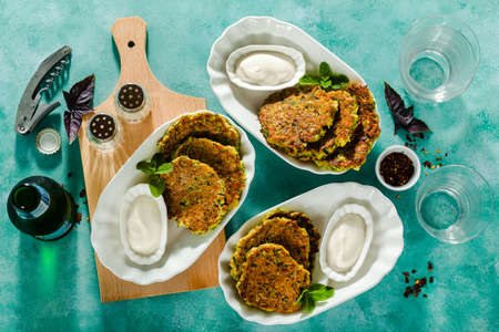 salted pancakes with zucchini and chickpea flour with spicy yoghurt sauce with beer on the table. summer vegan snack for family or lunch for friendsの写真素材