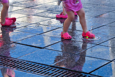 children play with water jets in a fountainの写真素材