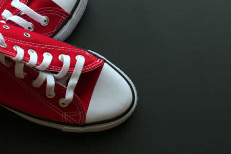 bright red sneakers on a natural dark blurry backgroundの写真素材
