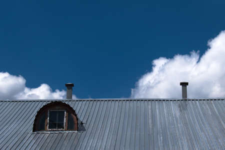 iron roof with attic window on blue sky backgroundの写真素材