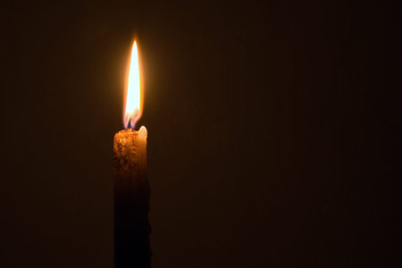 candle burns with a bright flame on a blurred background