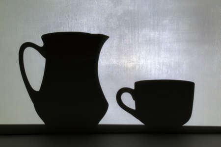 shadow from jug and mug on blurred white wall backgroundの写真素材