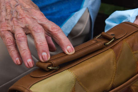 elderly woman hand touches the handbagの写真素材
