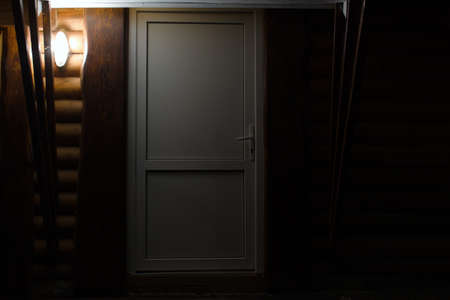 lantern illuminates the front door of wooden houseの写真素材