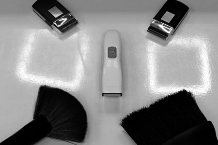 Hairdresser tool set. Brushes and trimmers in a beauty salon on a white table with reflections of...