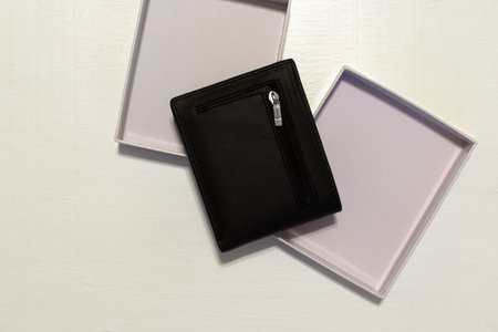 black wallet with packing box on blurred white background with place for text. flat lay