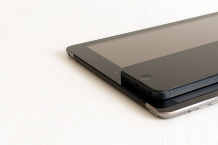 electronic gadgets smartphone and tablet in black on blurred painted white background