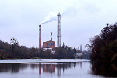 industrial landscape smoke from chimney of thermal power plant with reflection in waterの写真素材