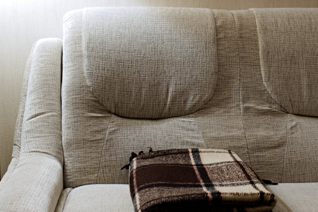 warm plaid on a soft sofa in soft light of floor lamp at home