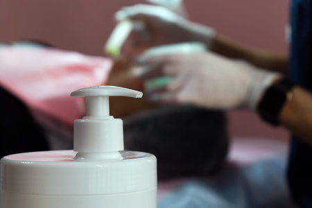 dispenser of bottle with cosmetic product on blurred background of beauty cabinet