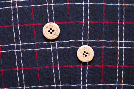 two identical buttons on a woolen fabric close-up with red and white stripes