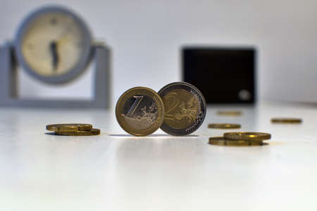 1 and 2 euros close up on blurred background with watch and walletの写真素材