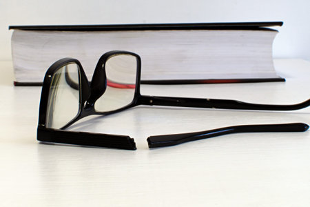 broken side piece of glasses close up in foreground and blurred background of broken glasses on...