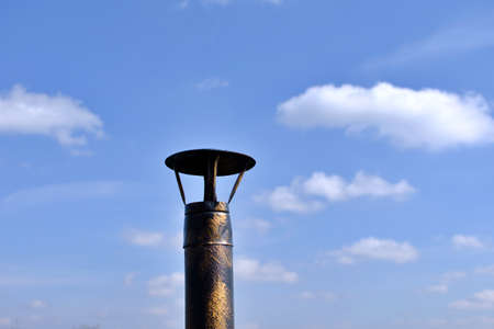 metal chimney pipe yellow black color against blue sky with cloudsの写真素材