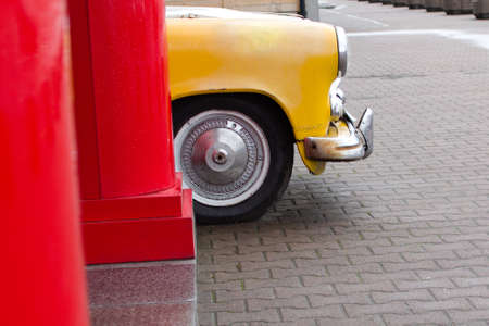 old yellow city car in modern parking lot behind red postの写真素材