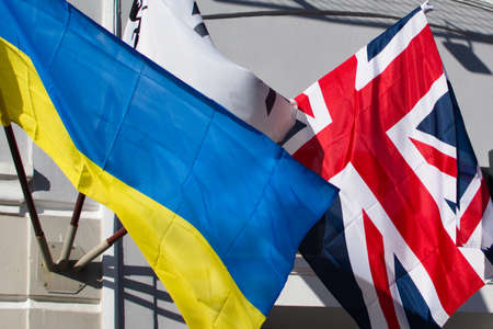 Ukrainian and United Kingdom flags waving on the wall of houseの写真素材