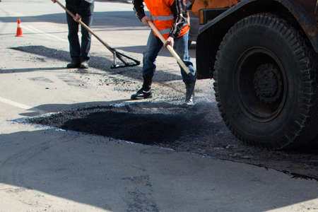 Road repair. Road workers leveling the asphalt mix. Ukraine Zhytomyr April 19, 2021のeditorial素材