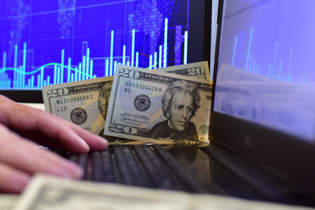 20 dollar banknotes on blurred background of computer screen and monitor with stock chart. Hands on...