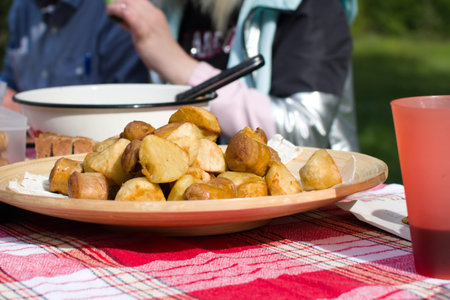 camping food. appetizing fried potatoes and sausages on table on blurred background. focus on...