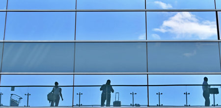 Reflection of people in windows of airport terminal on blurred windowの写真素材