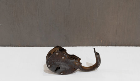 Old rusty padlock close-up on white table and grey wall