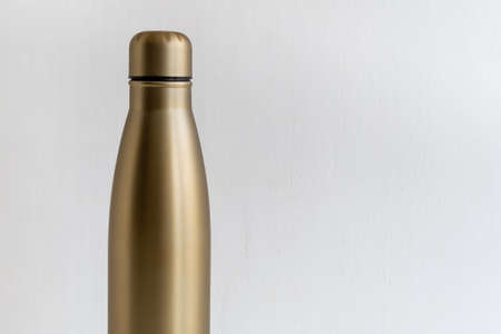 Golden metal bottle with cap on white wall backgroundの写真素材