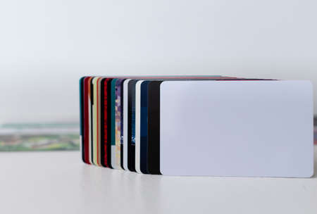 Blank white plastic card close-up in foreground in a row of other plastic customer loyalty cards on blurred white backgroundの写真素材